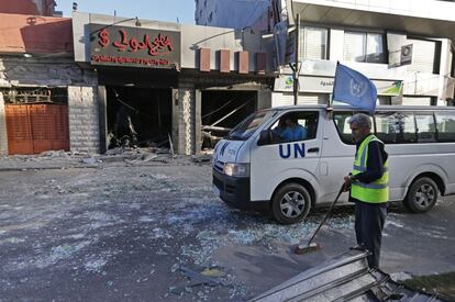 Un trabajador municipal palestino barre una calle en Ciudad de Gaza mientras pasa un vehículo de la ONU, durante la tregua humanitaria, que ha terminado a las dos de la tarde hora peninsular en España