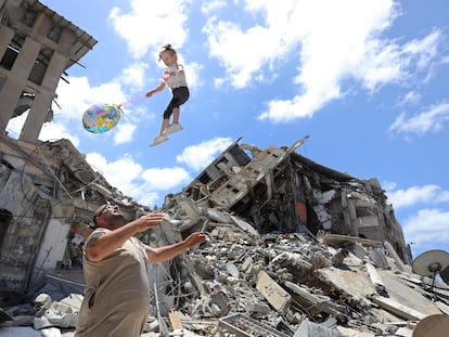 Um palestino brinca no sábado com uma garota ao lado dos escombros de uma casa bombardeada, em Gaza.