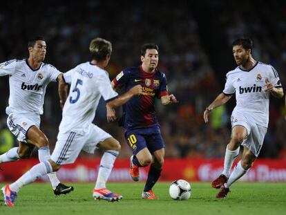 Messi conduce el balón ante rivales del Madrid.