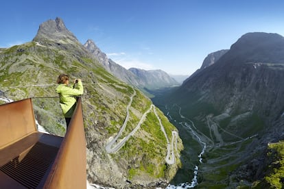 La carretera de montaña Trollstigen, en Rauma (Noruega) avanza ladera arriba como una zigzagueante y estrecha lengua de asfalto gracias a sus 11 recodos de 180 grados. En sus 106 kilómetros de recorrido salva una pendiente del 9%, atraviesa el paisaje del oeste del país como un pespunte gris sobre un fondo verde y ofrece vistas a cascadas, fiordos y valles. Lo circundan montes elevados con nombres majestuosos como Kongen (el Rey), Dronningen (la Reina) o Bispen (el obispo). Una vez arriba, hay un aparcamiento y a 10 minutos andando un mirador desde el que contemplar la cascada Stigfossen, con el agua cayendo más de 300 metros montaña abajo.