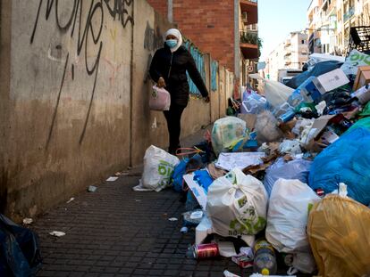 Una mujer esquiva las bolsas de basura acumuladas en la acera de una calle del centro de Salt