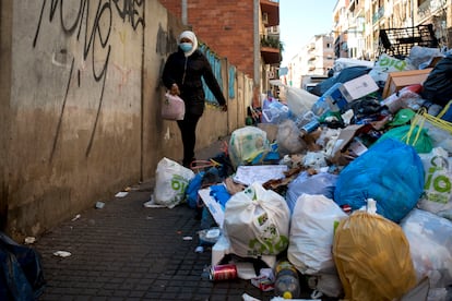Una mujer esquiva las bolsas de basura acumuladas en la acera de una calle del centro de Salt
