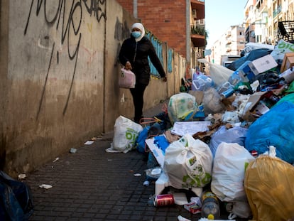 Una mujer esquiva las bolsas de basura acumuladas en la acera de una calle del centro de Salt