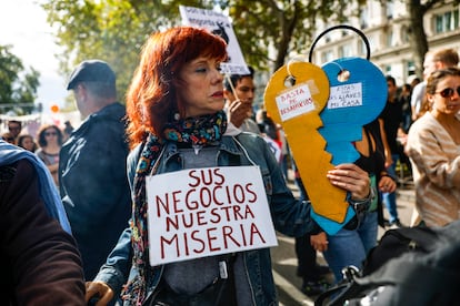 Una mujer sostiene unas llaves de cartón en las que se puede leer "Basta de desahucios" y "Estas son las llaves de mi casa".