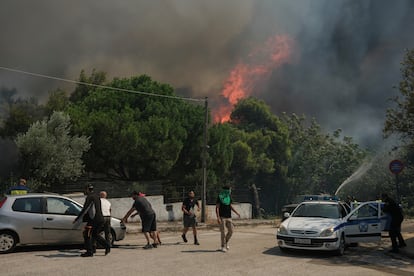 Las llamas aumentan mientras bomberos y voluntarios intentan extinguir un incendio forestal en Nea Penteli.