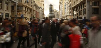 Un grupo de personas cruza un paso de peatones en la Gran Vía de Madrid.