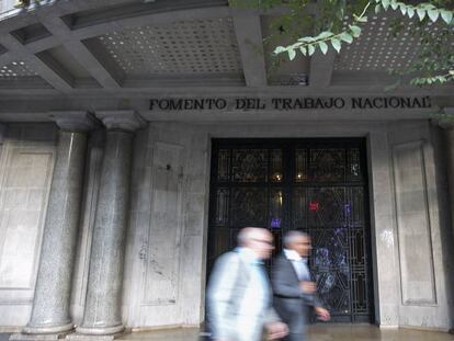 Dos hombres pasean por delante de la puerta de la Patronal