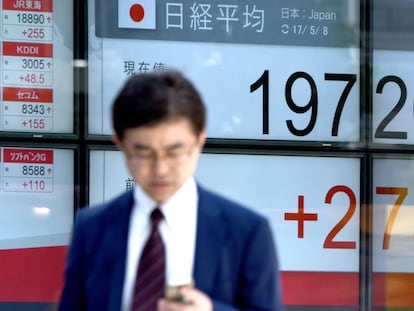 Un hombre pasea ante un panel que muestra la cotización del Nikkei japonés.
