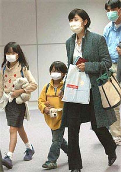 Pasajeros provenientes de Hong Kong llegan al aeropuerto de Tokio con sus mascarillas puestas para evitar la dispersión de la neumonía asiática.