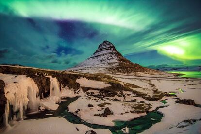 Luces celestes pertenecientes a una aurora boreal alumbran la montaña de la Iglesia, en kirjuffell (Islandia). Se trata de un lugar muy popular para los turistas que desean presenciar este fenómeno natural.