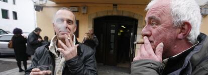 Dos hombres fuman y beben en la calle, frente a un bar en la calle de San Pedro de Hondarribia (Fuenterrabia, Guipúzcoa)
