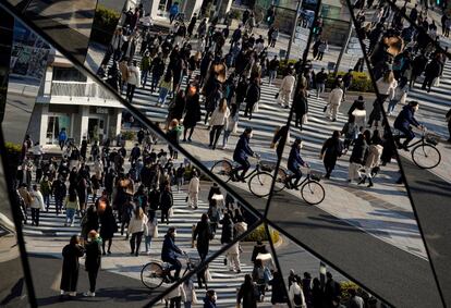 Varios transeúntes con máscaras se reflejan en los espejos en el distrito Omotesando en Tokio, Japón. Japón confirmó que el número de casos diarios de coronavirus superó la cifra de 100.000 por primera vez a medida que la variante ómicron se está extendiendo por todo el país.