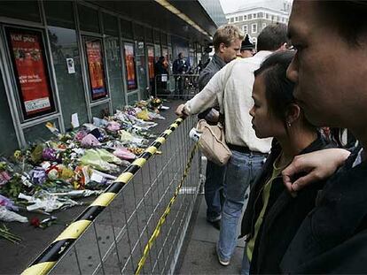 La gente observa los improvisados tributos florales dejados en las afueras de la estación de King's Cross.