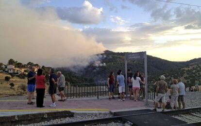 Varias personas contemplan desde la v&iacute;a del tren el incendio