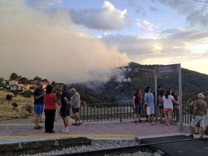 Varias personas contemplan desde la v&iacute;a del tren el incendio