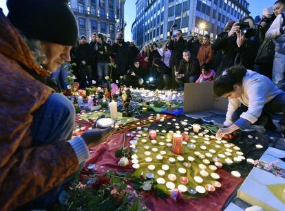 Un grupo de gente deposita flores y velas en la Plaza de la Bolsa, en Bélgica.