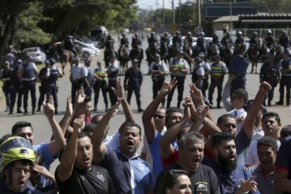 Motoboys bloqueiam entrada de distribuidora de combustíel em Brasília. Ao fundo, a polícia cerca o local. 