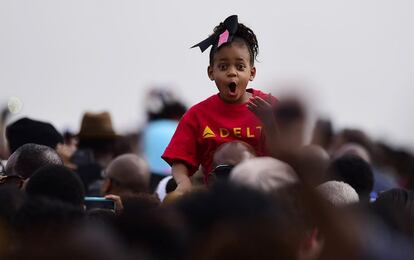 Una niña, que avanza a hombros de su padre, sobresale entre la multitud.