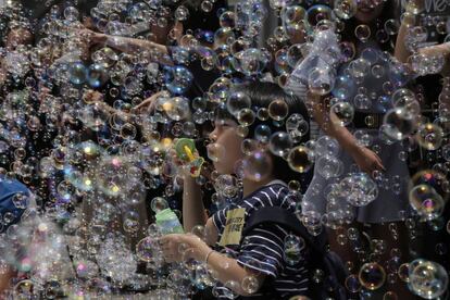 Un niño juega con pompas de jabón durante una instalación del artista japonés Shinji Ohmaki en Hong Kong.
