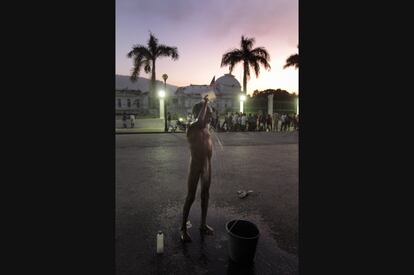 Un niño se ducha frente al Palacio Presidencial de Haití, donde miles de víctimas vivieron durante meses en un campamento improvisado en la calle (22/01/2010)