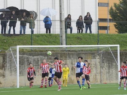 Partido de fútbol base con los padres fuera del recinto.