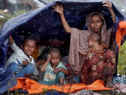 Refugiados da etnia rohingya se protegem da chuva com um plástico no campo de Cox’s Bazar, em Bangladesh