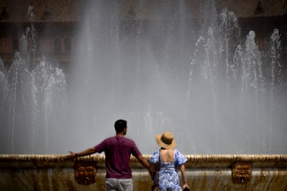 Dos personas junto a la fuente de la Plaza de España este lunes en Sevilla.
