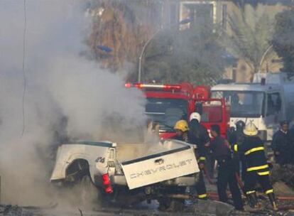 Los bomberos tratan de apagar los restos de uno de los coches bomba que han estallado hoy en el centro de Bagdad.