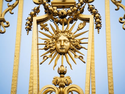 Detalle de la verja cubierta de pan de oro del Palacio de Versalles, con el símbolo de Luis XIV, el Rey Sol.