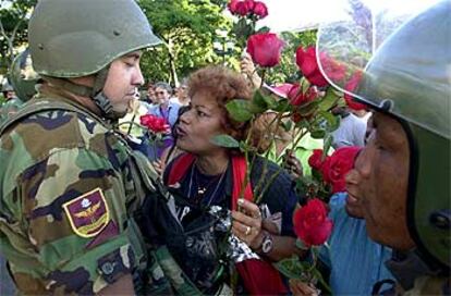 Un partidario de Chávez da flores a un guardia nacional ayer durante la marcha de los opositores.