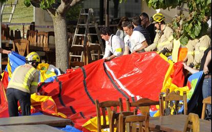 Operarios y bomberos retiran el castillo hinchable.