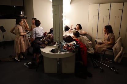 En esta fotografa, algunos miembros del coro charlan y hacen deberes frente a espejos rodeados de bombillas en el camerino durante su descanso.