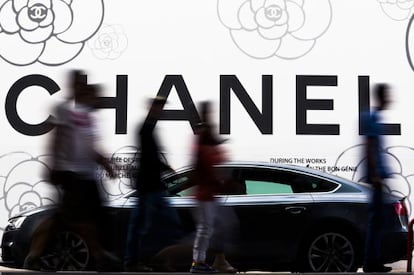 Varias personas pasean por delante de un cartel de Chanel en Ginebra (Suiza). 