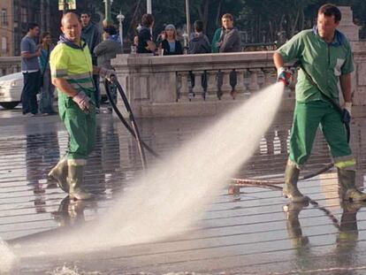 Operarios de servicio municipal de limpieza riegan la calle en Bilbao.