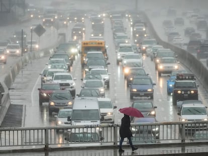 Un transeúnte camina con un paraguas mientras conductores conducen a través de la lluvia en Hollywood, Los Angeles, Marzo 10, 2023.
