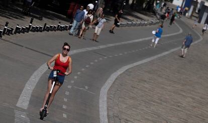 Una usuaria de patinete circula por un carril bici.