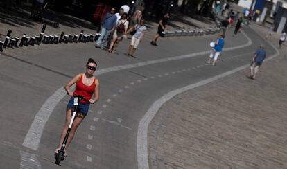 Una usuaria de patinete circula por un carril bici.