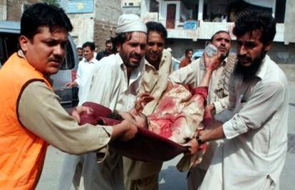 Unos pakistaníes trasladan el cuerpo de un hombre herido en un atentado bomba en un templo de la zona de Jamrud, a un hospital local en Peshawar.