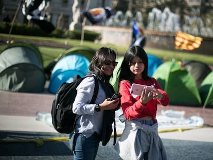 Dos turistes davant de l'acampada de plaça Catalunya.