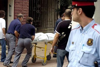 Miembros de los servicios funerarios retiran el cadáver de una de las dos jóvenes.