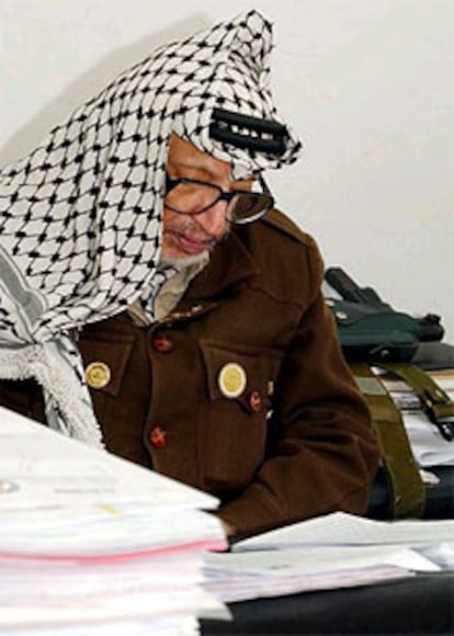 El presidente palestino, Arafat, junto a su arma, en su despacho de Ramala.