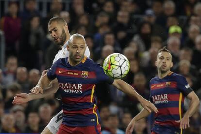 Javier Mascherano del Barcelona, protege el balón de Karim Benzema durante el clásico.