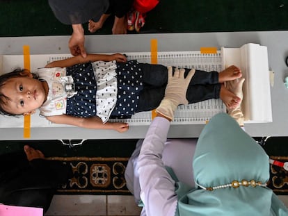 Miembros de un equipo sanitario miden la altura de una niña pequeña durante un chequeo médico masivo en un puesto de Banda Aceh, Indonesia.
