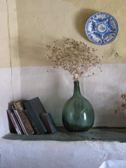 Interior con libros, damajuana y plato de cerámica.