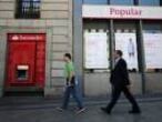 Dos viandantes pasan frente a una sucursal del Banco Santander y una del Banco Popular en Madrid