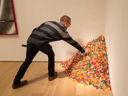 A visitor picks up a piece of candy from Felix Gonzalez-Torres's 'Untitled (Portrait of Ross in L.A.),' which is currently on display at the Smithsonian Institution in Washington, D.C.. It’s now being displayed as 'Untitled,' omitting the name of Gonzalez-Torres' partner, who died of AIDS in 1991.