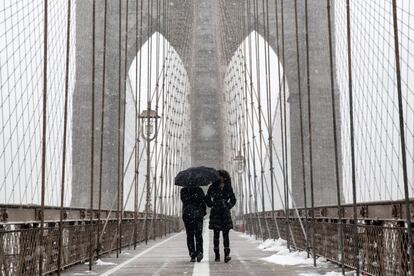 Dos personas caminan bajo la nieve por el puente de Brooklyn, en Nueva York.