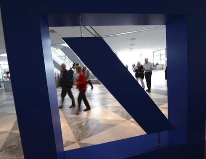 Un grupo de personas pasan por delante del logotipo de Deutsche Bank.