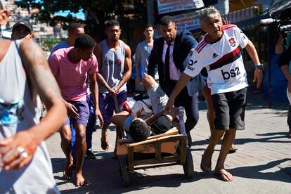 Residentes de la favela transportan en una carretilla a un hombre herido durante la operación policial.