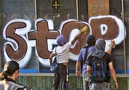 Varios jóvenes hacen pintadas durante las protestas antiglobalización de junio en Barcelona.